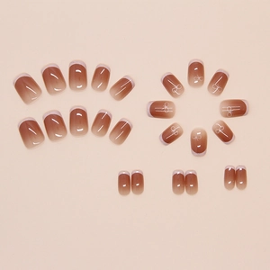 Detail of ombre brown press-on nails with white French tips and elegant bow accents