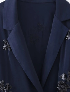 Detailansicht des dunkelblauen Satin-Blazers mit feiner schwarzer Paillettenstickerei am Kragen