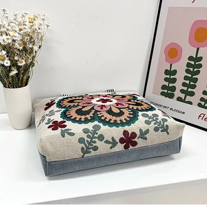 Detail of vintage floral embroidery on cream woven canvas shoulder bag with stripe handle