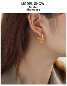 Close-up of a model wearing gold geometric hoop earrings with circular disk charms