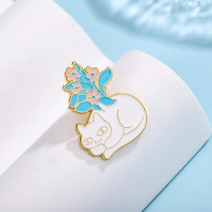 Detail of white cat enamel pin with blue and pink flowers on its back in gold plating