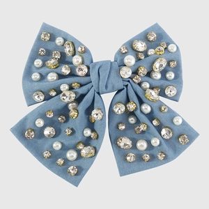 Dettaglio del fermaglio a fiocco in denim blu con perle eleganti e strass brillanti