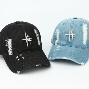 Detailed view of distressed denim baseball caps with metallic star rivets and frayed holes