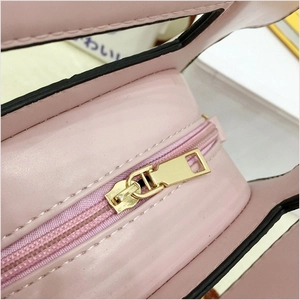 Close-up of pink litchi grain leather bag with smooth golden zipper and black edge paint