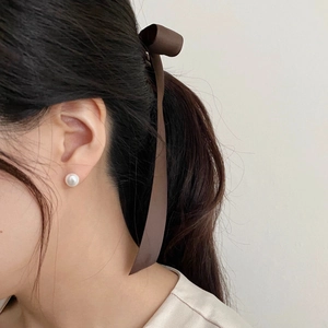 Side view of model wearing a minimalist 8mm round white pearl earring with a brown hair bow