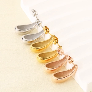 Detailed view of teardrop earrings in silver, gold, and rose gold finishes on white steps
