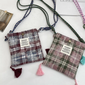 Detail of plaid crossbody bag with colorful tassels and woven rope shoulder strap