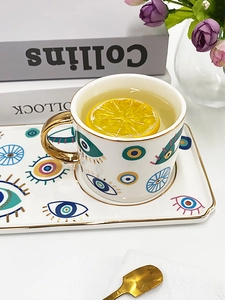 Detail of evil eye ceramic cup with gold handle and matching saucer set for afternoon tea