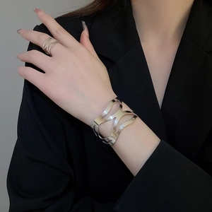 Detail of silver hollow geometric bracelet and matching ring set on model's hand