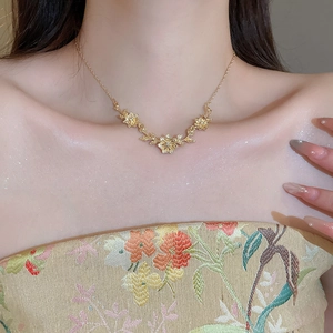 Detail of elegant gold flower and leaf pendant necklace worn on a collarbone