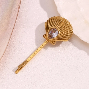 Golden scallop hair clip with teardrop zircon on wet pink surface and white shell
