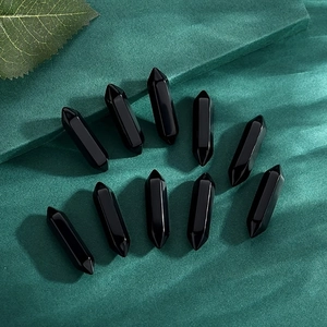 Set of ten black hexagonal crystal points displayed on a textured green fabric background