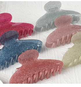 Detailed view of colorful glitter acrylic shark hair claws on white fabric