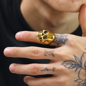 Dettaglio di un anello a teschio dorato in stile punk con incisioni su un dito maschile