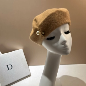 Detailed texture of camel wool beret with elegant white pearl and gold bead accents