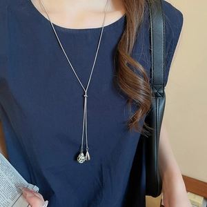 Close-up of a silver lariat necklace with asymmetrical spotted stone and metal teardrops