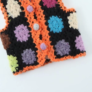Détail d'un gilet au crochet fait main avec motifs floraux colorés et texture en tricot rustique