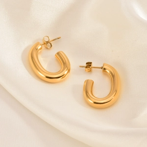 Detailed macro view of 18K gold-plated stainless steel U-shaped earrings on beige silk