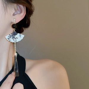 Détail d'une boucle d'oreille en forme d'éventail avec imprimé bambou et pompon résine