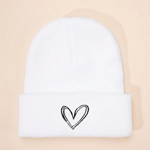 Close-up of white knit beanie texture and black embroidered heart on the folded cuff