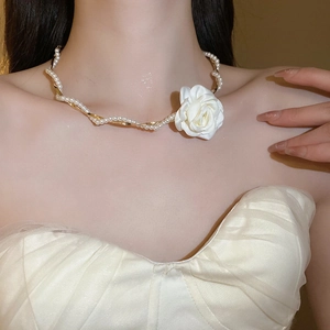 Gros plan d'un collier vintage français avec chaîne dorée, perles et grande fleur en tissu