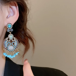 Detail of vintage bohemian tassel earrings with turquoise stones and gold hollow patterns
