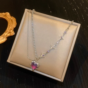 Detail of baroque pearl necklace with purple heart pendant and star charms on beige padding