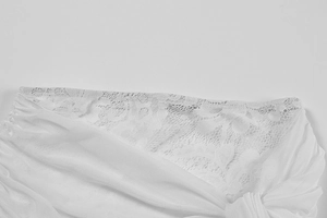 Macro view of white floral lace patchwork and draped mesh fabric detail on women dress
