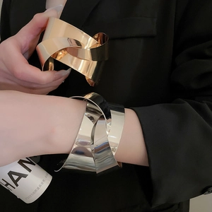Close-up of knot-design open metal bangles in polished gold and silver finishes