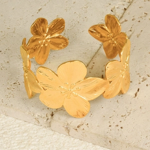 Close-up of golden flower cuff bracelet showing brushed metal texture and floral petals