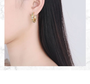 Close-up of gold chain-style hoop earrings with cubic zirconia on a female model
