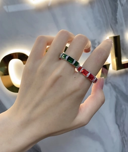 Detail of luxury emerald and ruby rectangle cut rings on hand with marble background