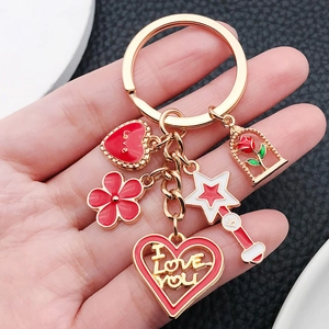 Golden heart keychain with red enamel rose, star wand and love charms on black background