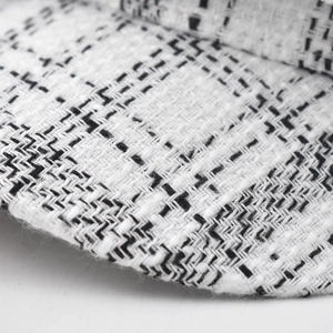 Macro view of the black and white tweed fabric texture on a vintage newsboy cap