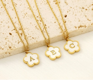 Detailed macro of 18K gold clover necklaces with shell alphabet A, B, and C charms