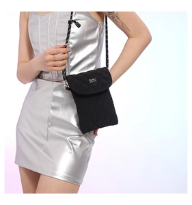 Detail of black quilted crossbody phone bag with woven Fashion label and cord strap