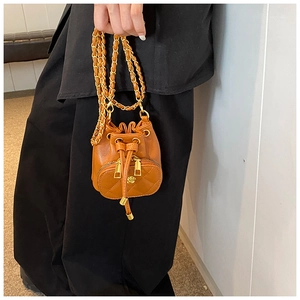Detail of caramel bucket bag with quilted texture, chain strap and metal flower zipper