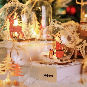 Macro detail of glass Christmas ornaments with elk and Santa wood inserts and faux snow