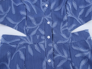Détails de la robe en jean bleue avec texture jacquard feuille et découpes latérales