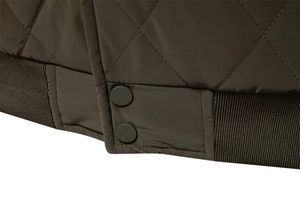 Close-up of diamond-quilted jacket featuring metal snap buttons and ribbed knit hemline
