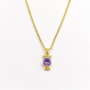 Macro detail of owl pendant with purple zircon inlay and fine gold plated chain