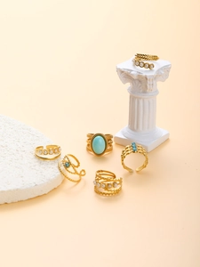 Detail of vintage gold rings with turquoise, pearls and leaf motif on beige stone display