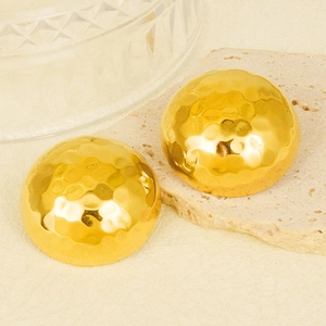 Vue macro des boucles d'oreilles hémisphères dorées martelées sur pierre