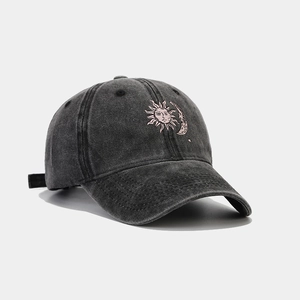 Detail of pink embroidered sun and moon on a vintage washed grey cotton baseball cap