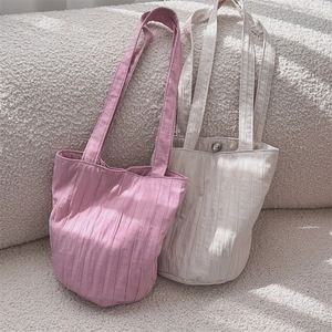 Detalle del bolso de cubo plisado minimalista con textura vertical y cierre metálico