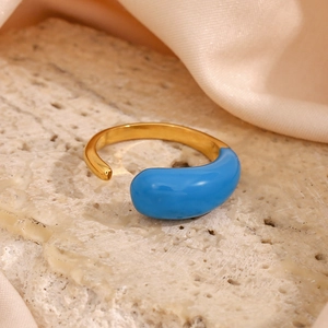 Macro shot of gold adjustable waterdrop ring with blue enamel on silk and stone base
