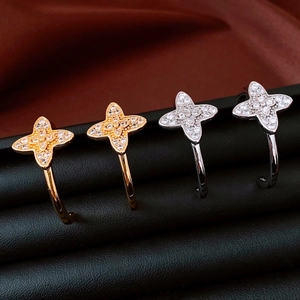 Macro shot of gold and silver C-shaped flower earrings with zircons on a leather stand