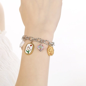 Detail eines silbernen Gliederkettenarmbands mit verschiedenen Anhängern am Handgelenk