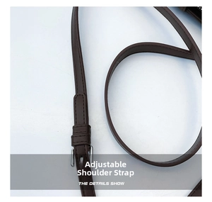 Detail showing the adjustable dark brown leather shoulder strap with silver buckle and stitching