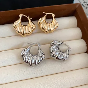 Polished croissant wave shell earrings in gold and silver finishes in a jewelry box
